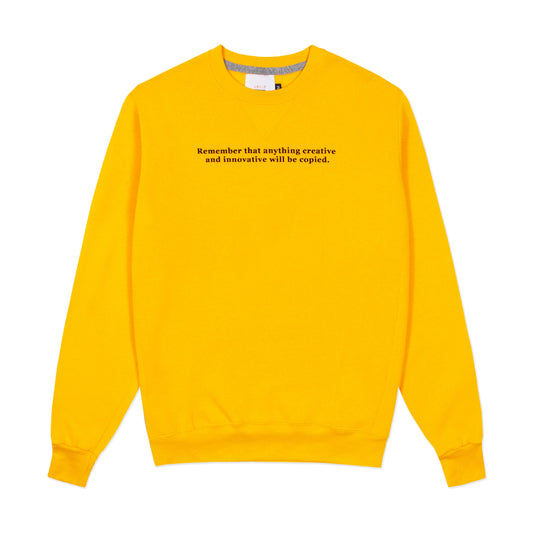 Yellow crewneck sweatshirt with "Remember that anything creative and innovative will be copied." on the front.