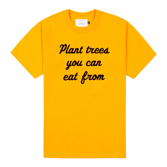 Yellow t-shirt with "Plant trees you can eat from" printed in cursive across the front.