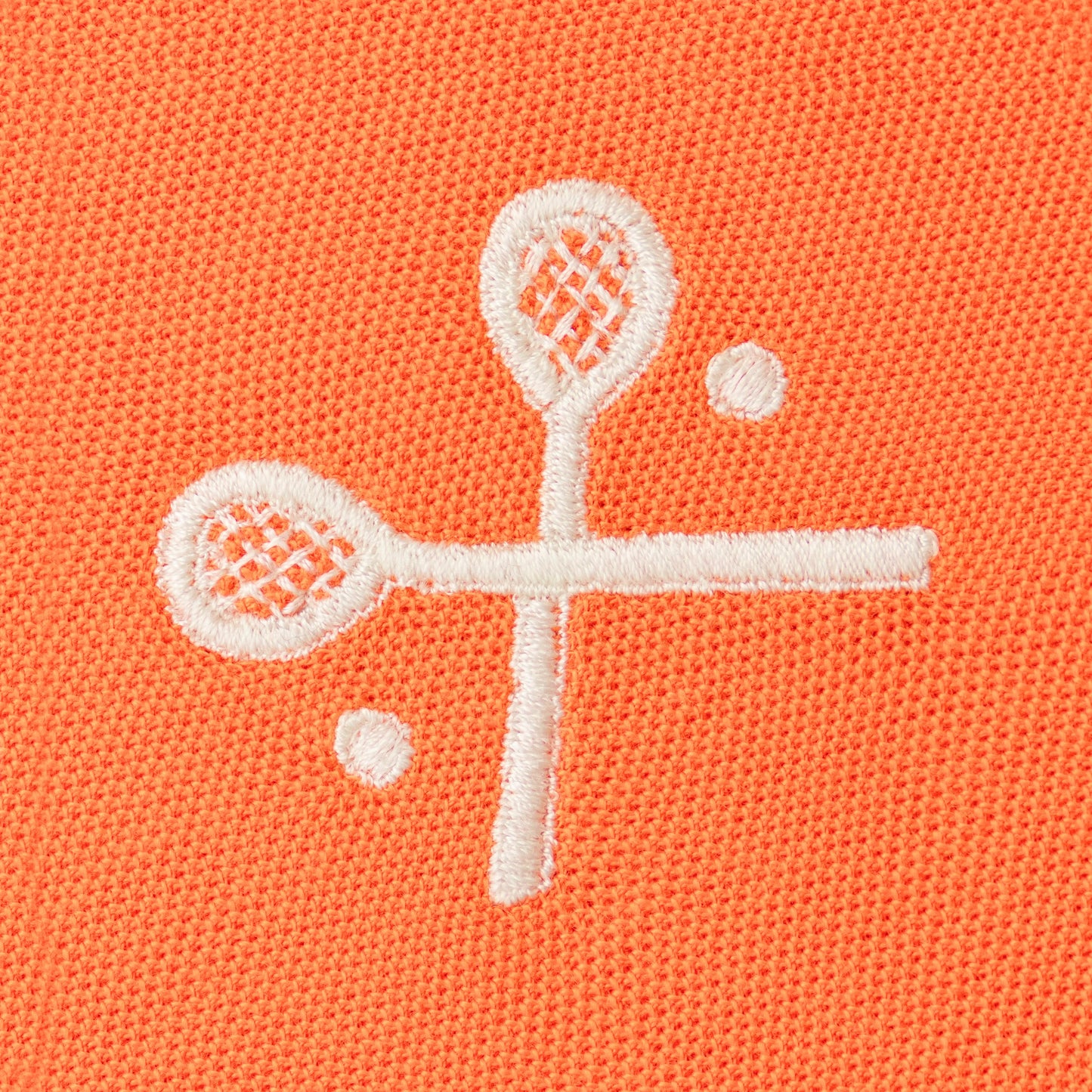 White embroidered crossed racquets motif on orange polo.