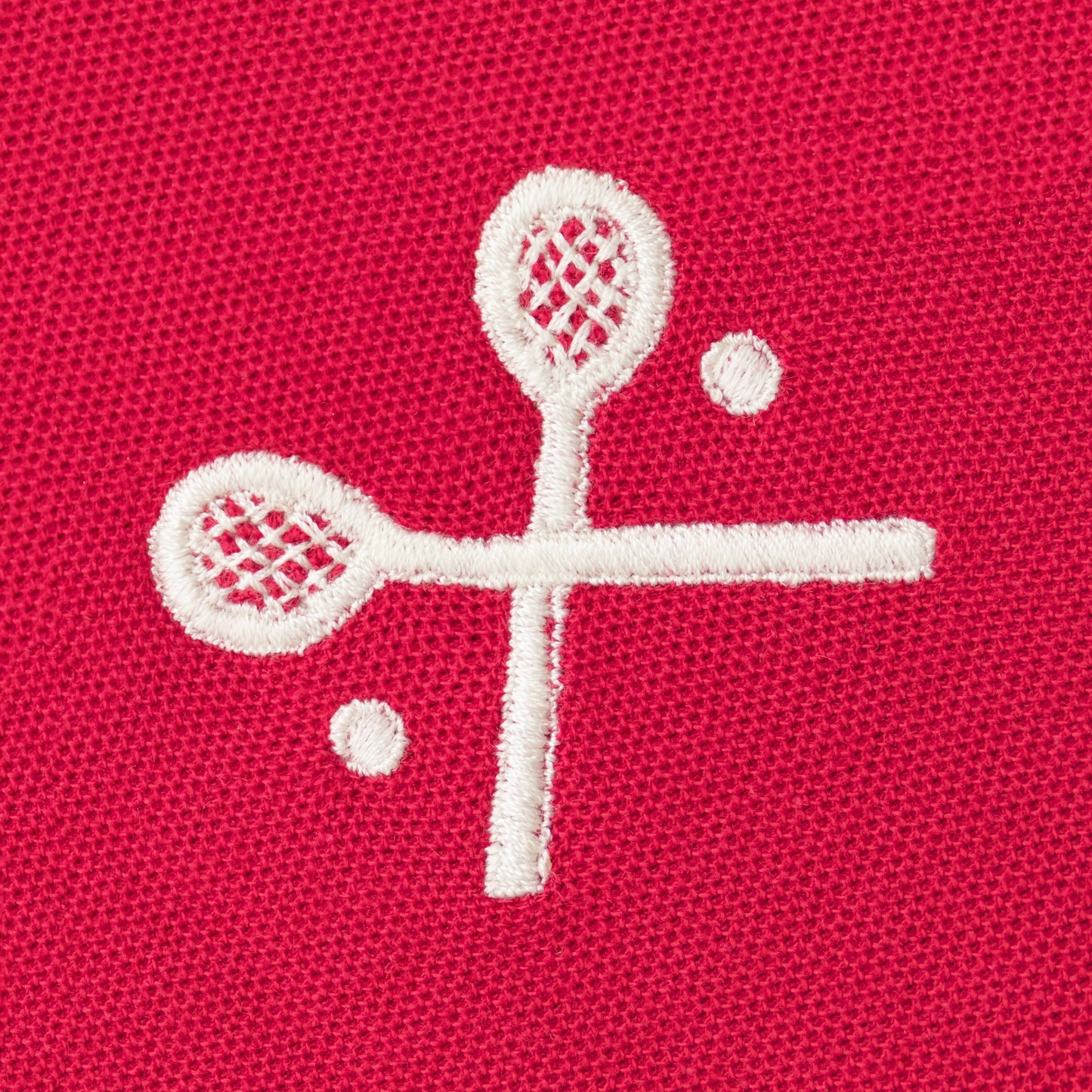 White embroidered crossed racquets motif on red polo.