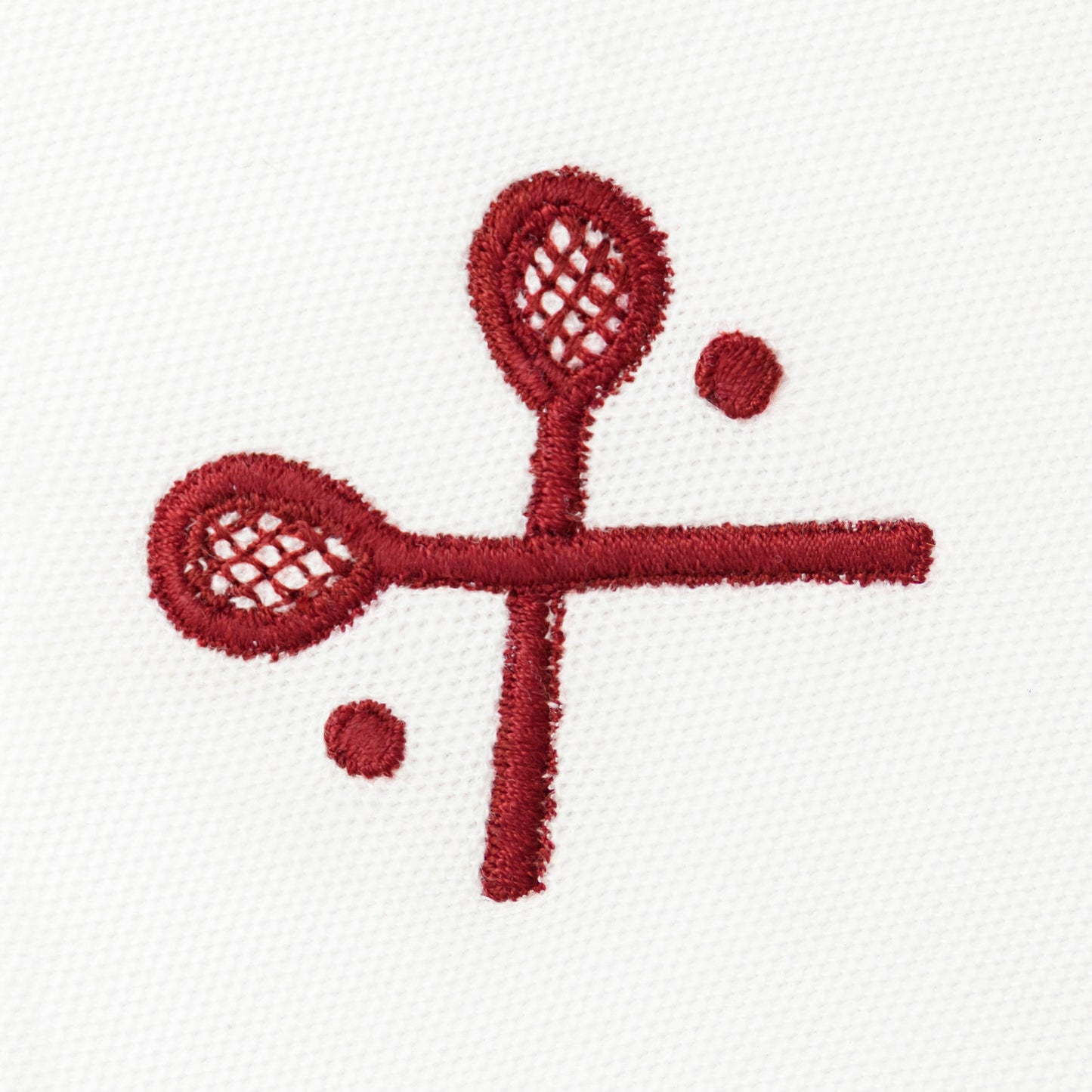 Red embroidered crossed racquets motif on white polo.