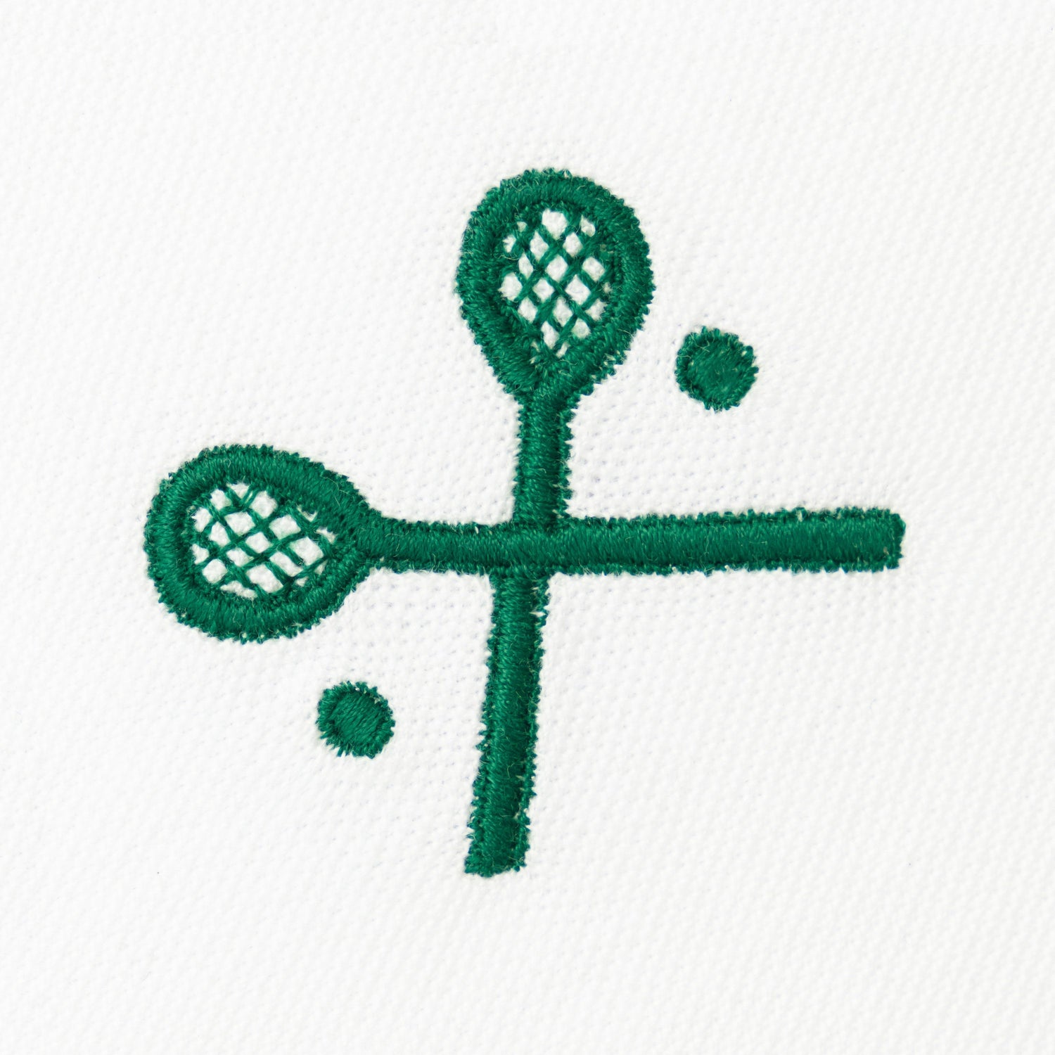 Green embroidered crossed racquets motif on white polo.