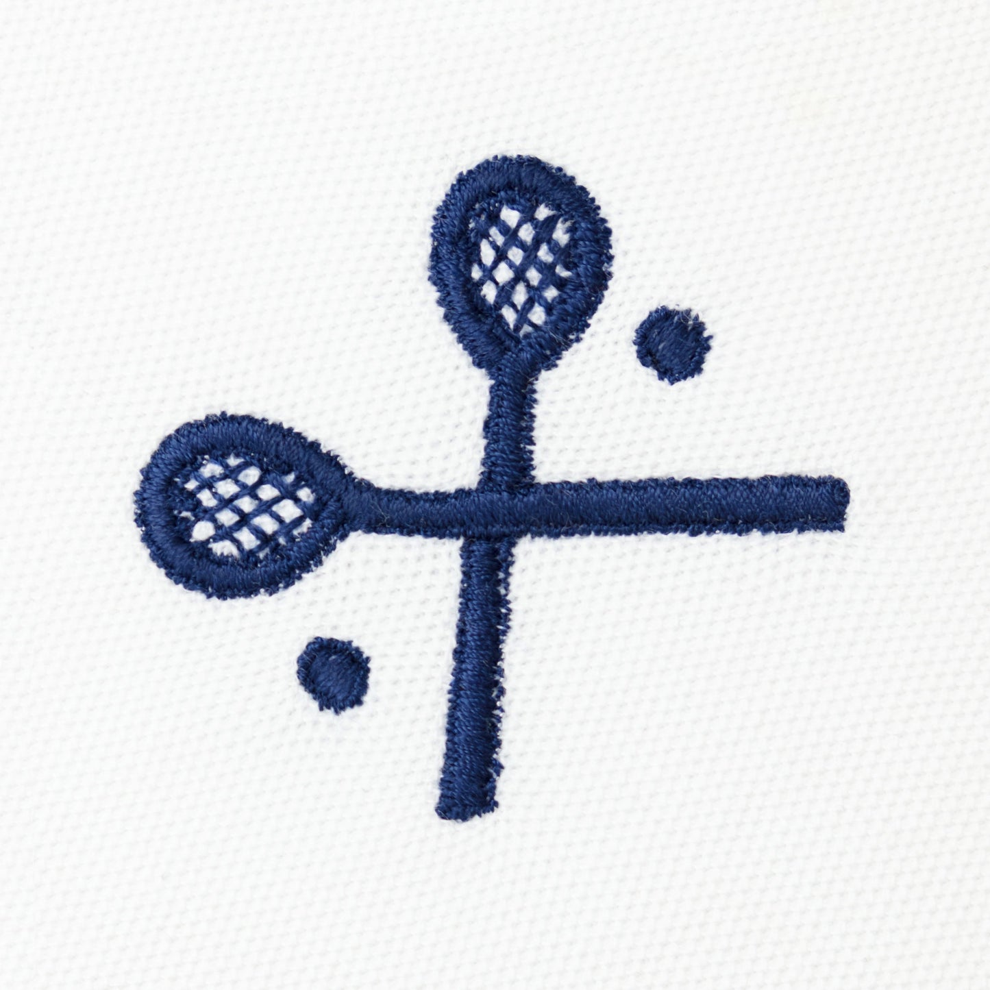 Navy embroidered crossed racquets motif on white polo.